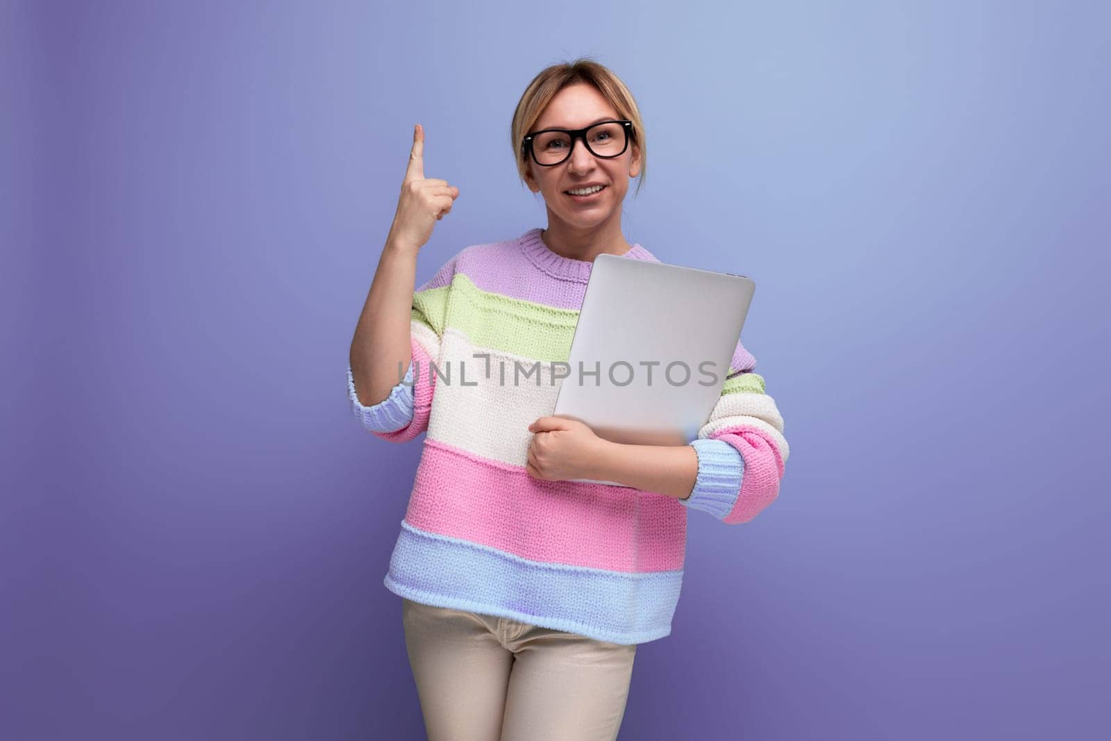 successful blond woman freelancer with a laptop in her hands shows copy space on a purple background.
