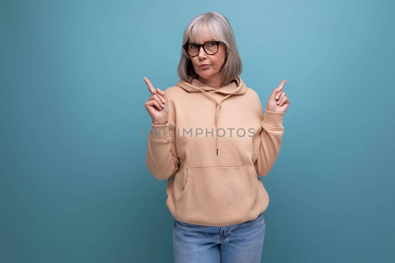 middle aged business woman with gray hair crossed her arms and prays on studio background with copy space.