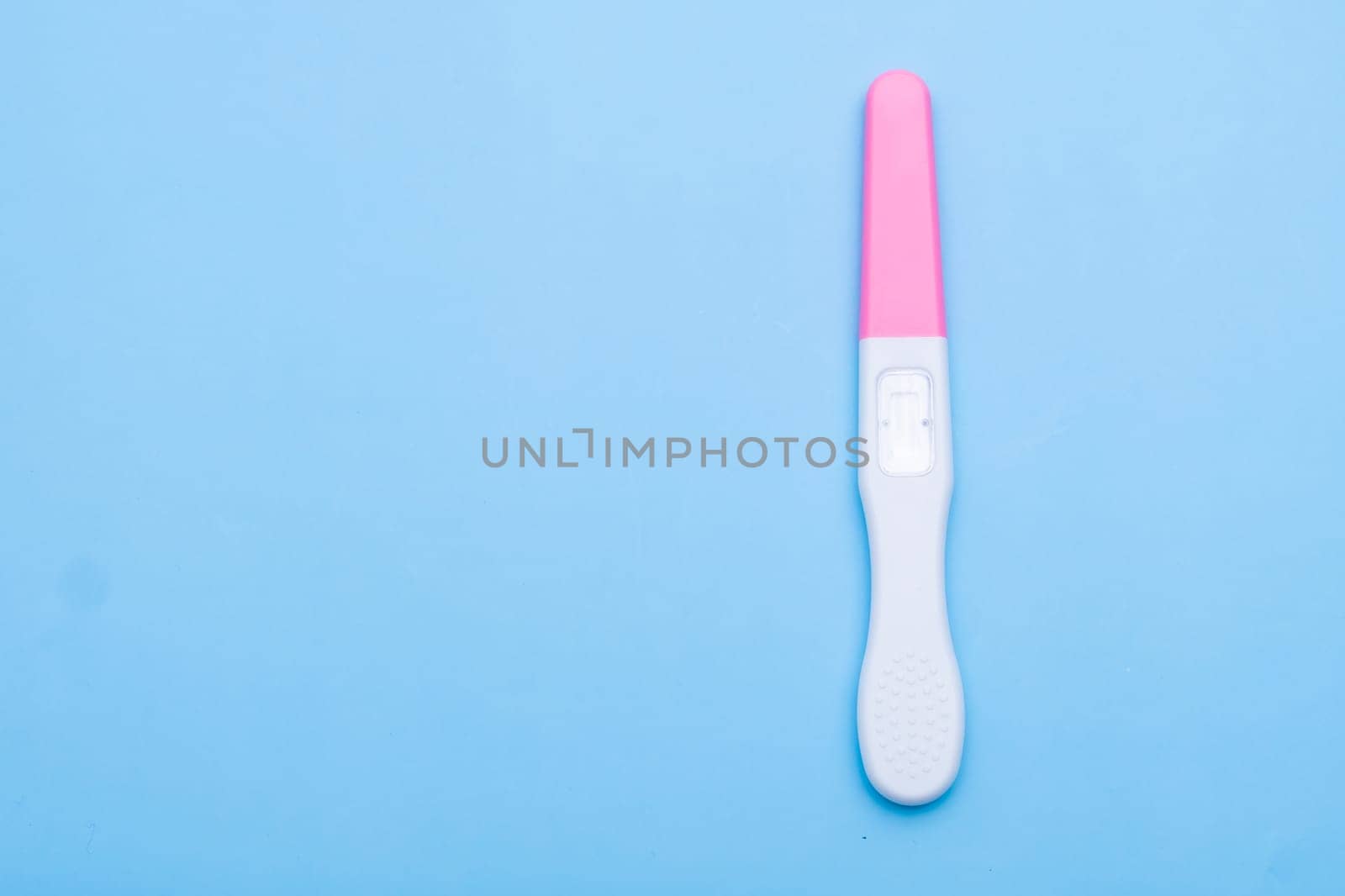 Unused pink and white pregnancy test on the blue background with copy space