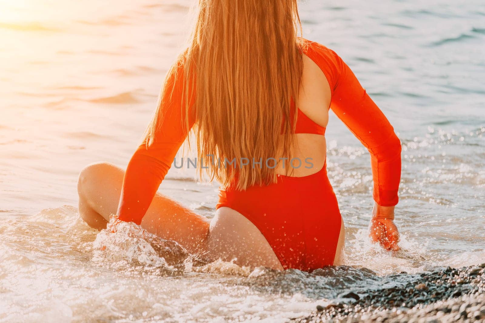 Young Caucasian woman in red swimsuite having fun in the waves of the sea which are splashing her on the coast. Vacation The concept of an travel, relax, active and healthy life in harmony with nature by panophotograph