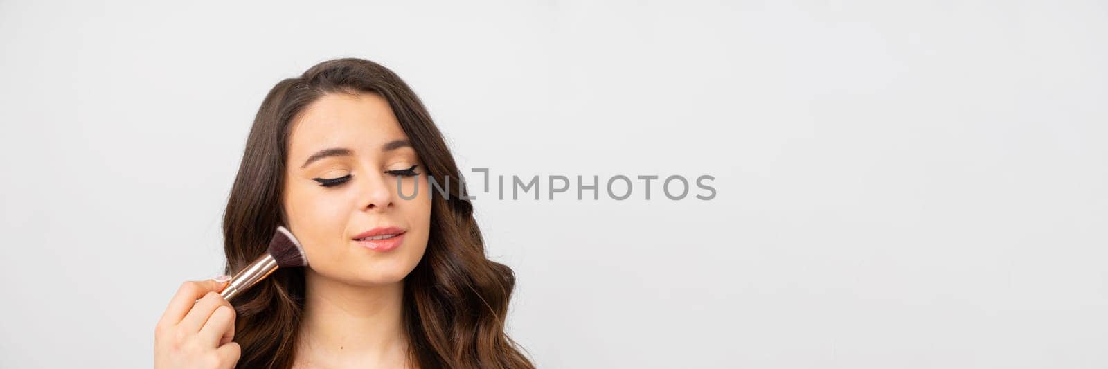 Young brunette model poses in camera applying powder on face by vladimka