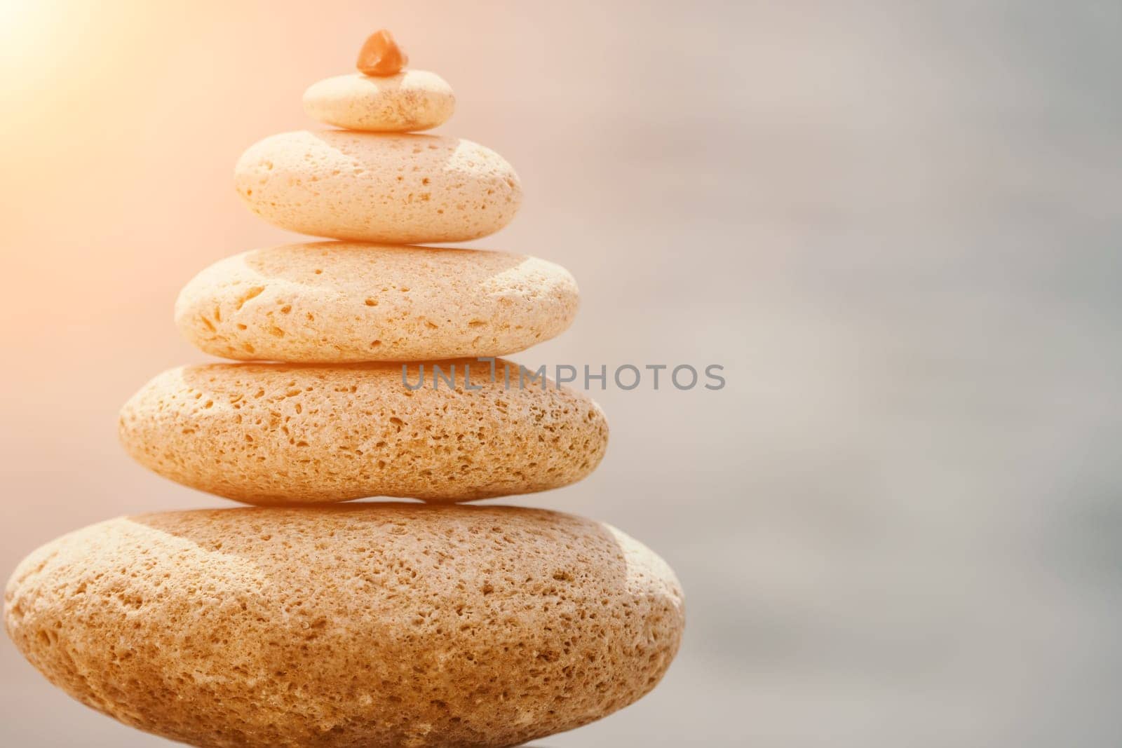 Pyramid stones on the seashore with warm sunset on the sea background. Happy holidays. Pebble beach, calm sea, travel destination. Concept of happy vacation on the sea, meditation, spa, calmness.