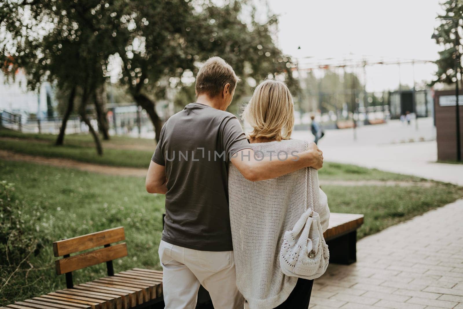 An adult mature happy romantic couple in love outdoors in city street park. A blonde caucasian man and woman spend time together. Senior wife and husband walking outside on town square
