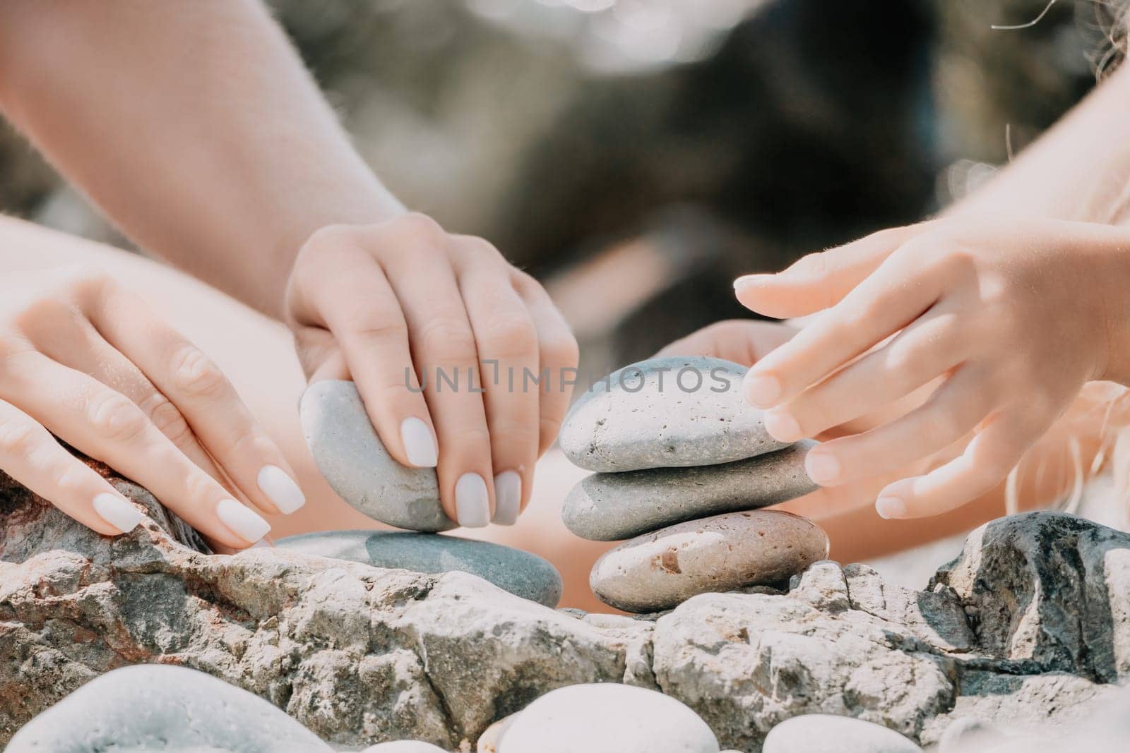 Balanced Pebbles Pyramid on the Beach on Sunny Day and Clear Sky at Sunset. Blue Sea on Background Selective focus, zen stones on sea beach, meditation, spa, harmony, calm, balance concept.