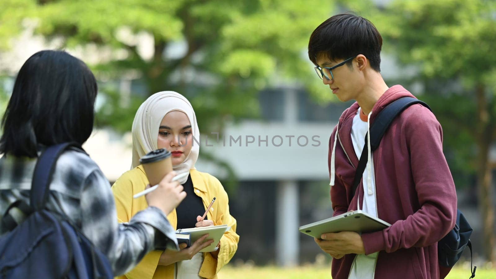 Group of students talking to each other after classes while walking in university outdoors. Youth lifestyle and community.