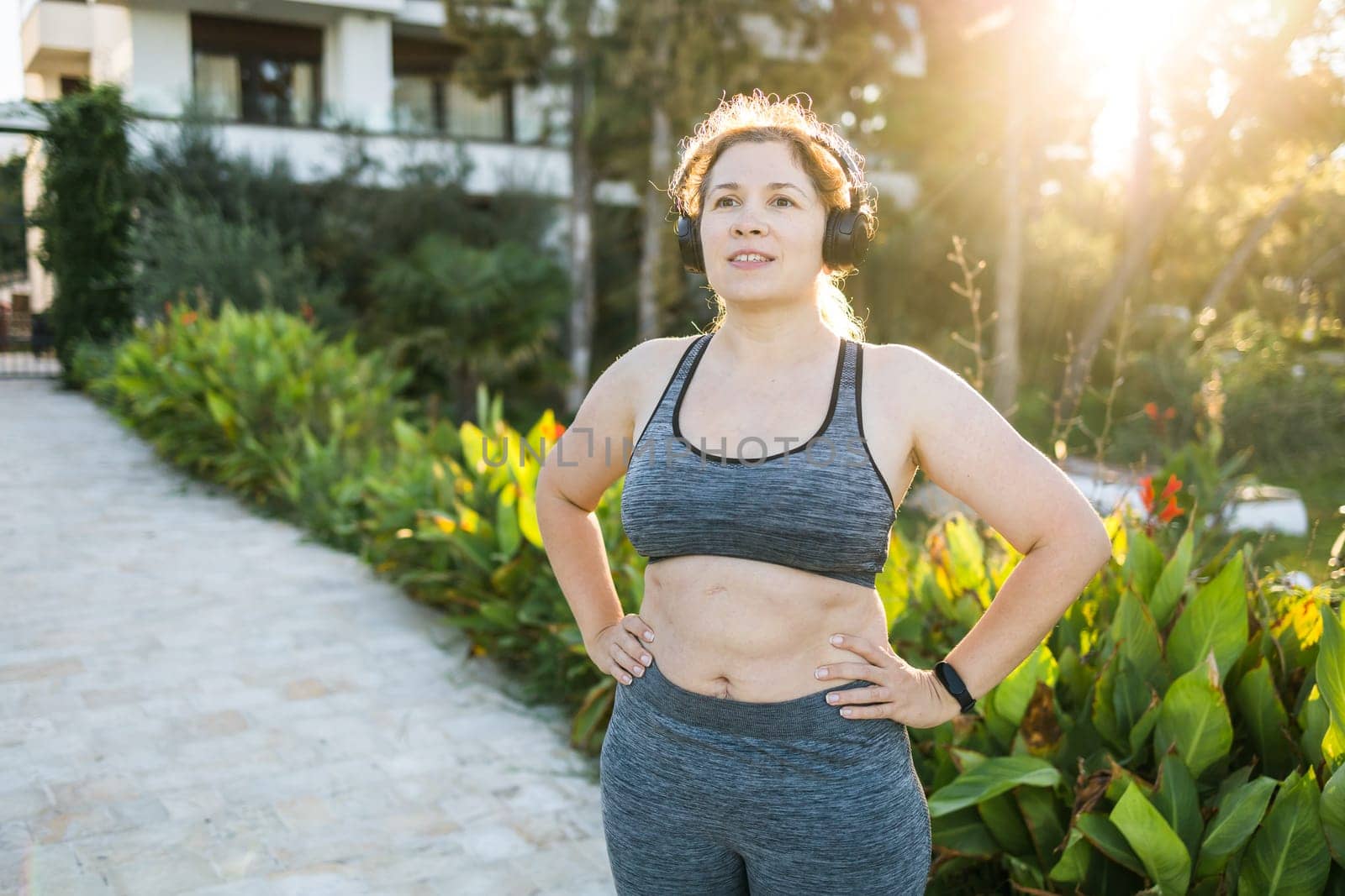 Fat woman and sports. Girl doing exercise for weight loss in the fresh air and smiling after training. Copy space and empty place for text or advertising by Satura86