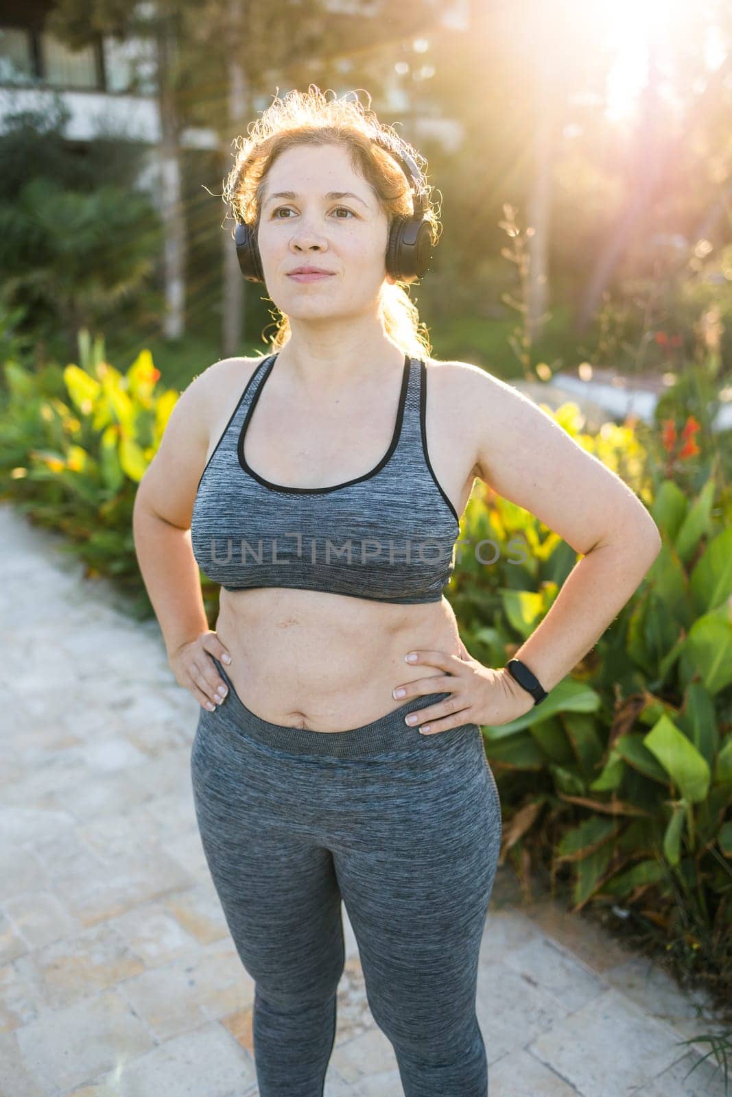 Fat woman and sports. Girl doing exercise for weight loss in the fresh air and laughing in camera after training.