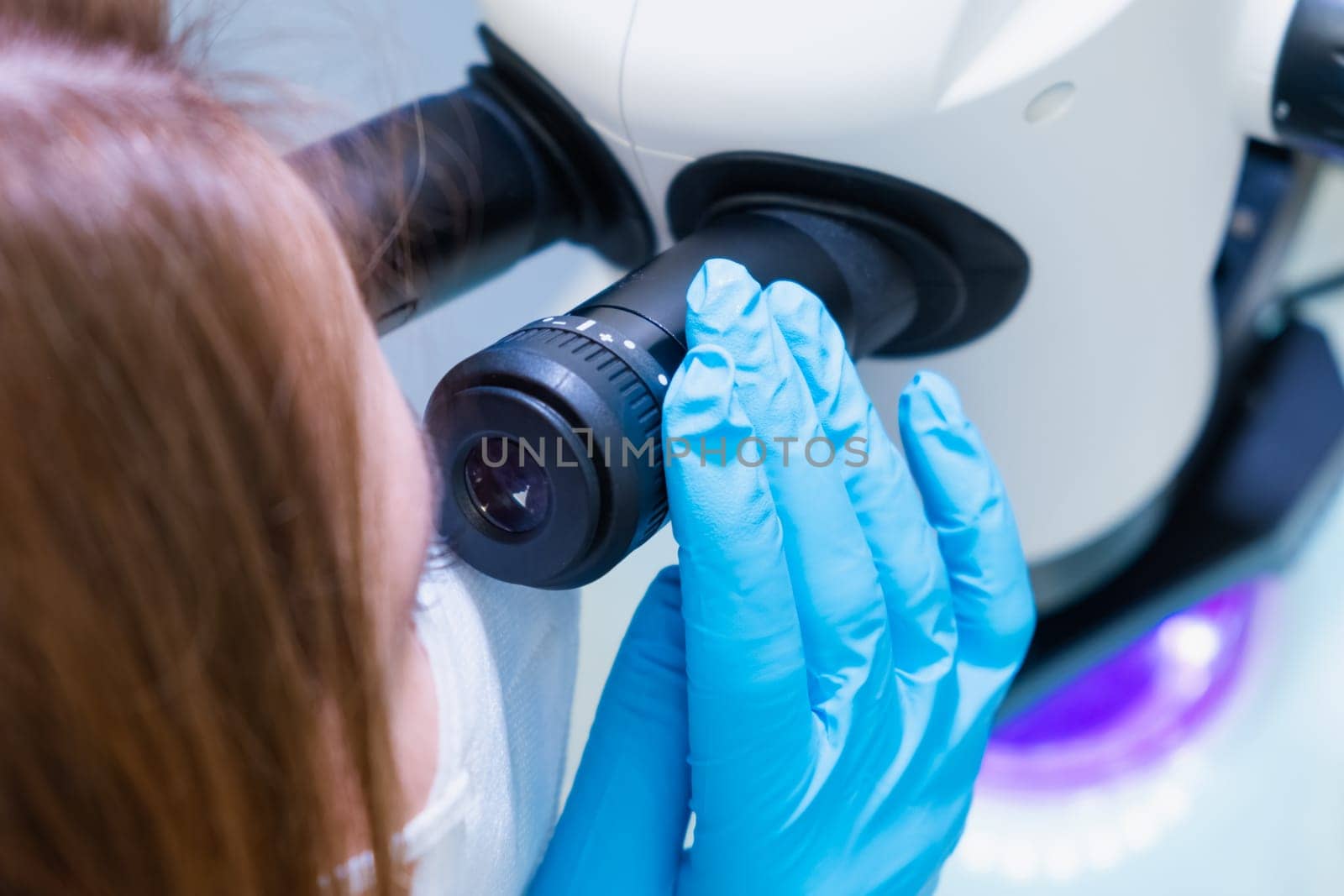 Professional female scientist doing experiment with electronic microscope in scientific genetic research laboratory