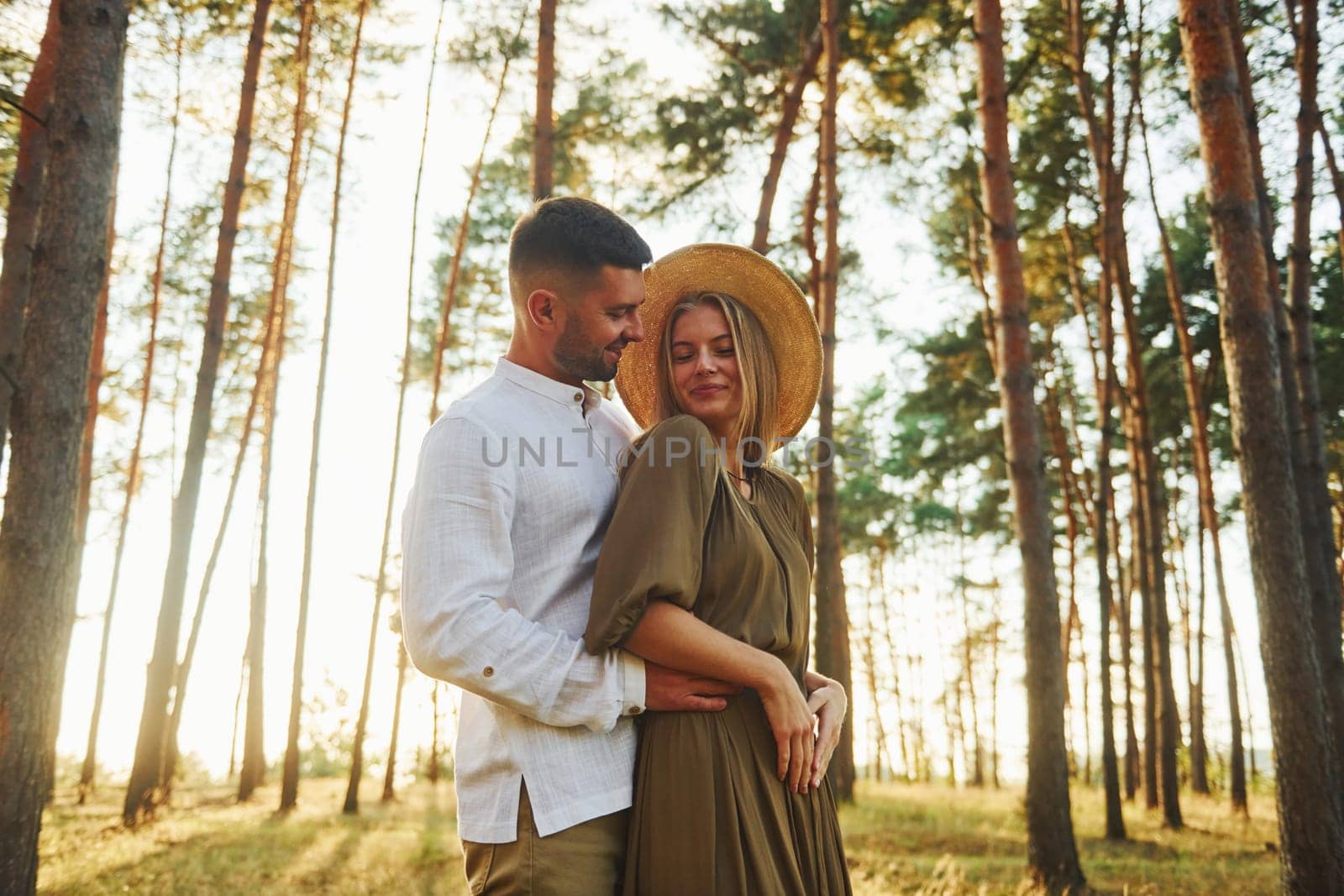 Beautiful sunlight. Happy couple is outdoors in the forest at daytime.