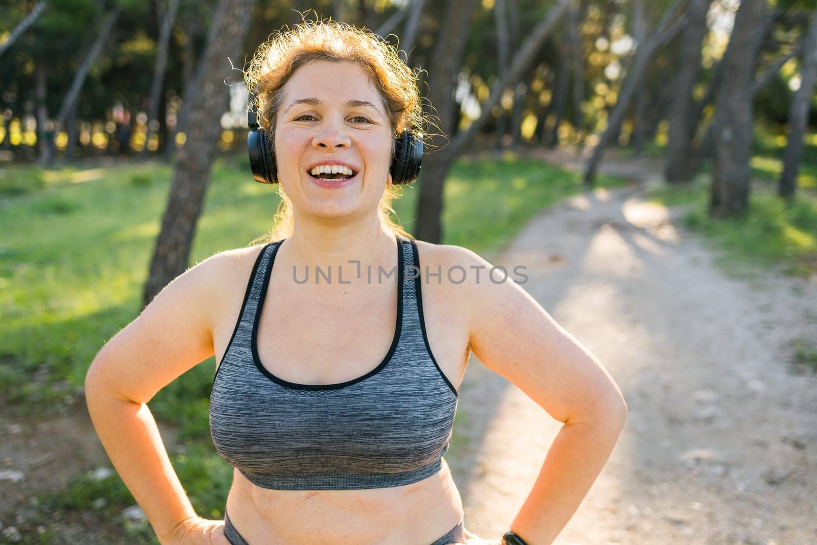 Fat woman and sports. Girl doing exercise for weight loss in the fresh air and laughing in camera after training. Copy space and empty space for text or advertising by Satura86