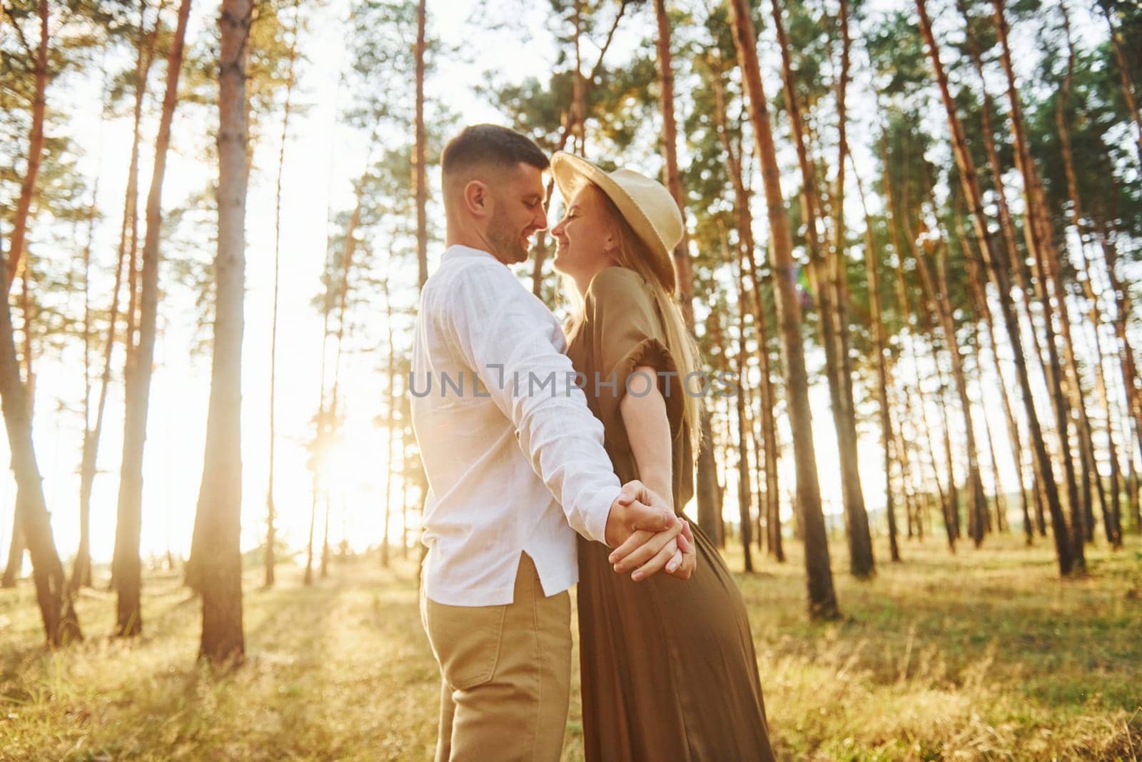 Warm weather. Happy couple is outdoors in the forest at daytime.