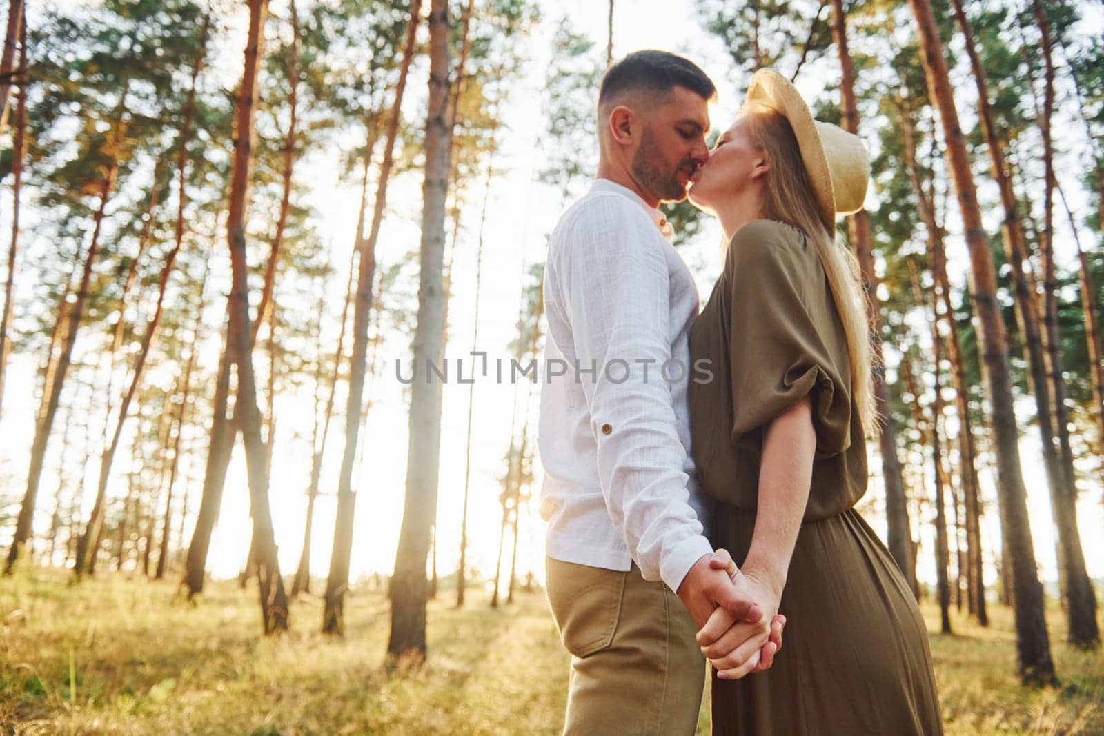 Holding each other by the hands. Happy couple is outdoors in the forest at daytime.