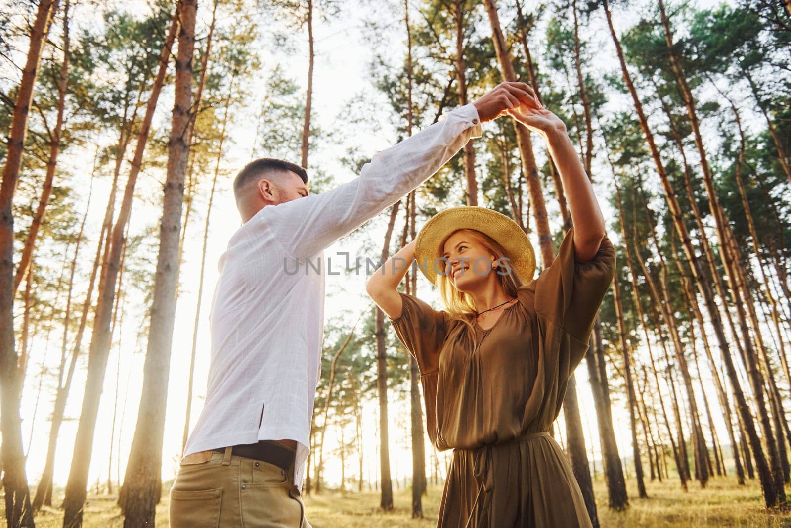 Holding each other by the hands. Happy couple is outdoors in the forest at daytime.