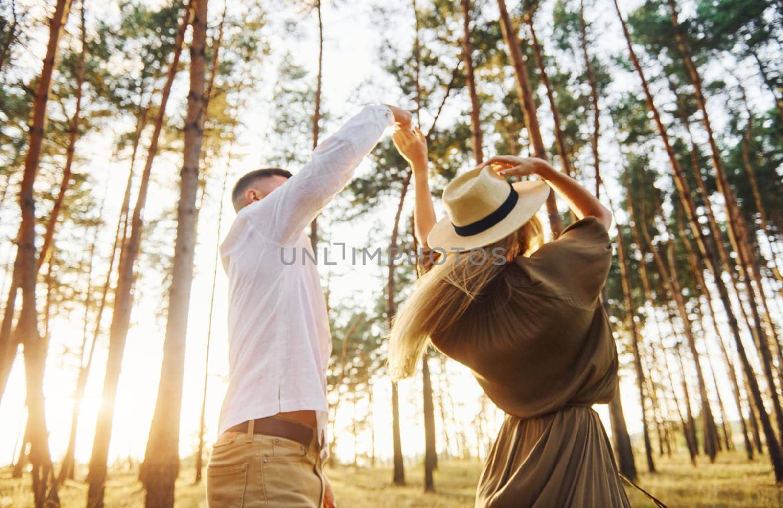 Holding each other by the hands. Happy couple is outdoors in the forest at daytime.