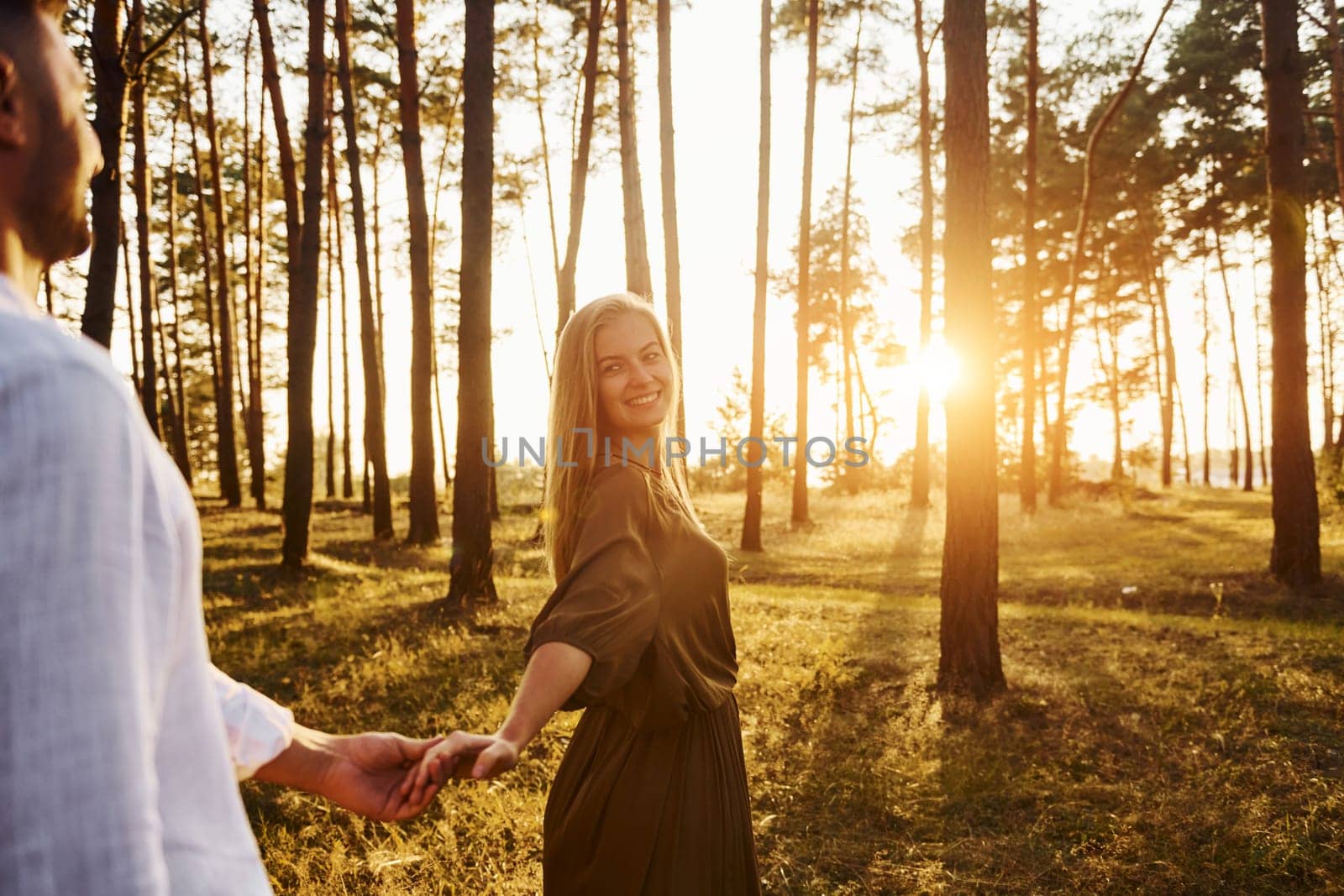 Follow me, concept. Happy couple is outdoors in the forest at daytime.