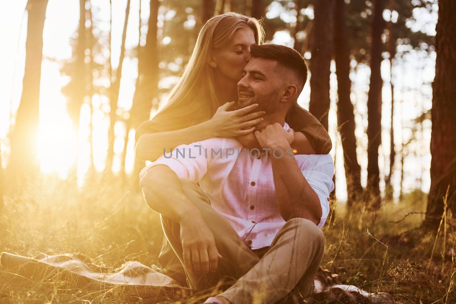 Sitting on the ground. Happy couple is outdoors in the forest at daytime by Standret
