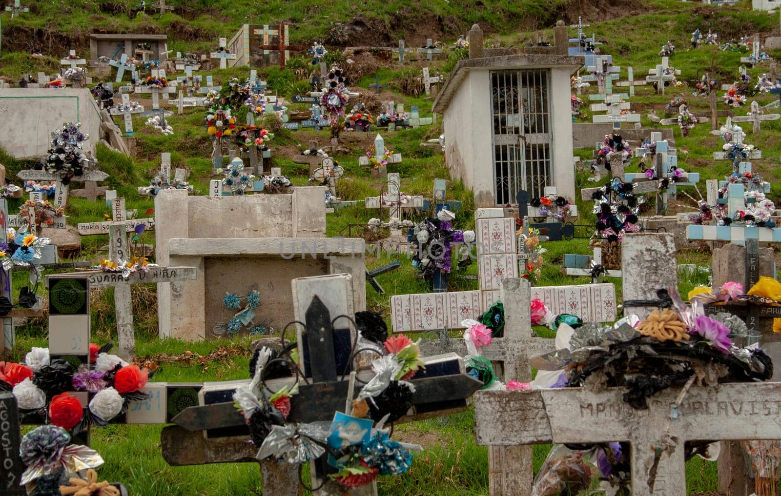 In memory of loved ones: a photo of a Latin American cemetery on a mountain with floral arrangements and stone crosses. High quality photo