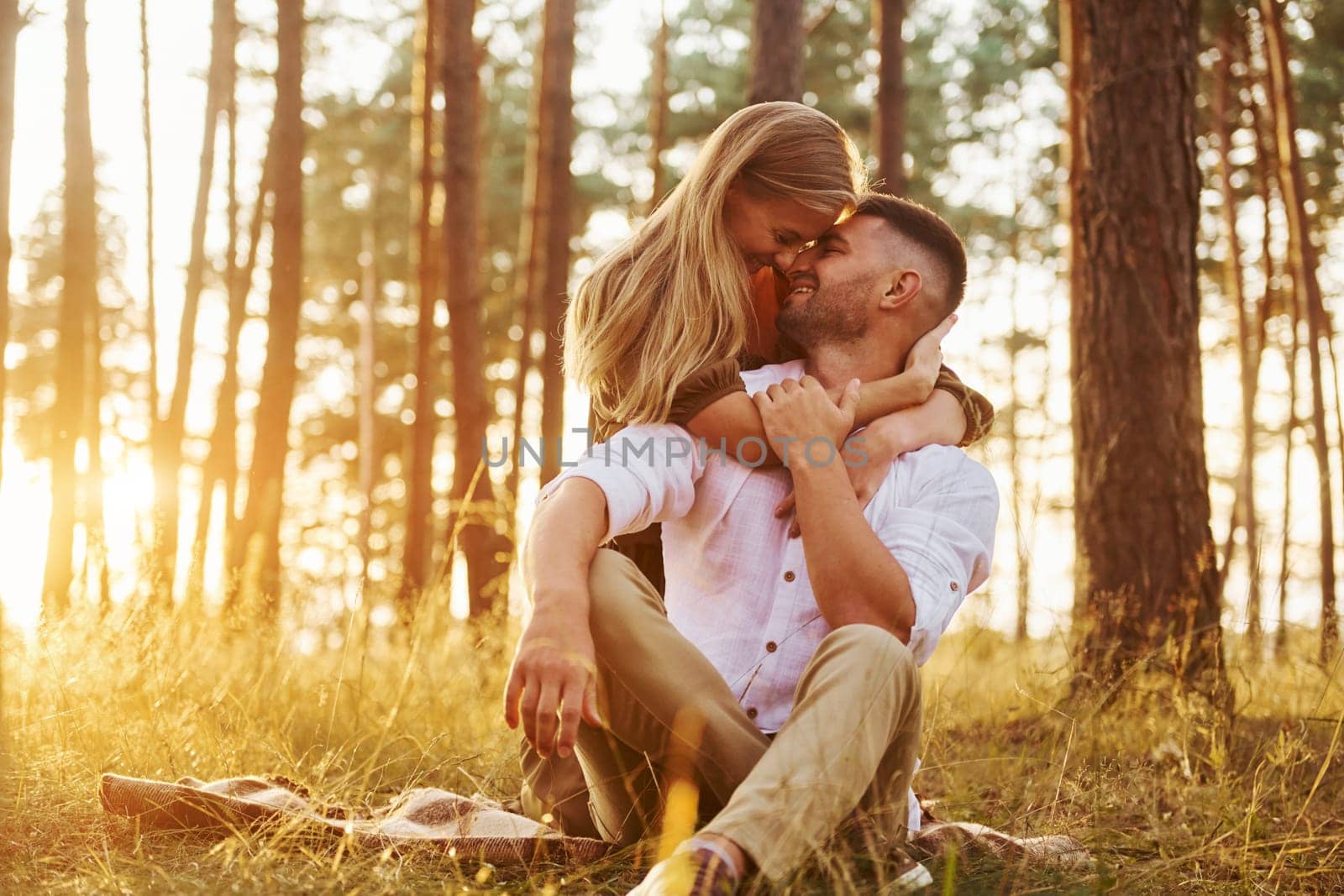 Sitting and embracing each other. Happy couple is outdoors in the forest at daytime by Standret