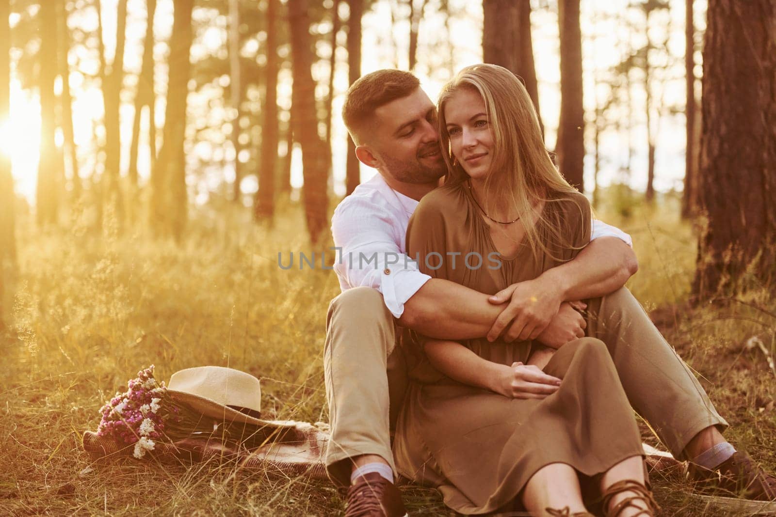 Sitting and embracing each other. Happy couple is outdoors in the forest at daytime.