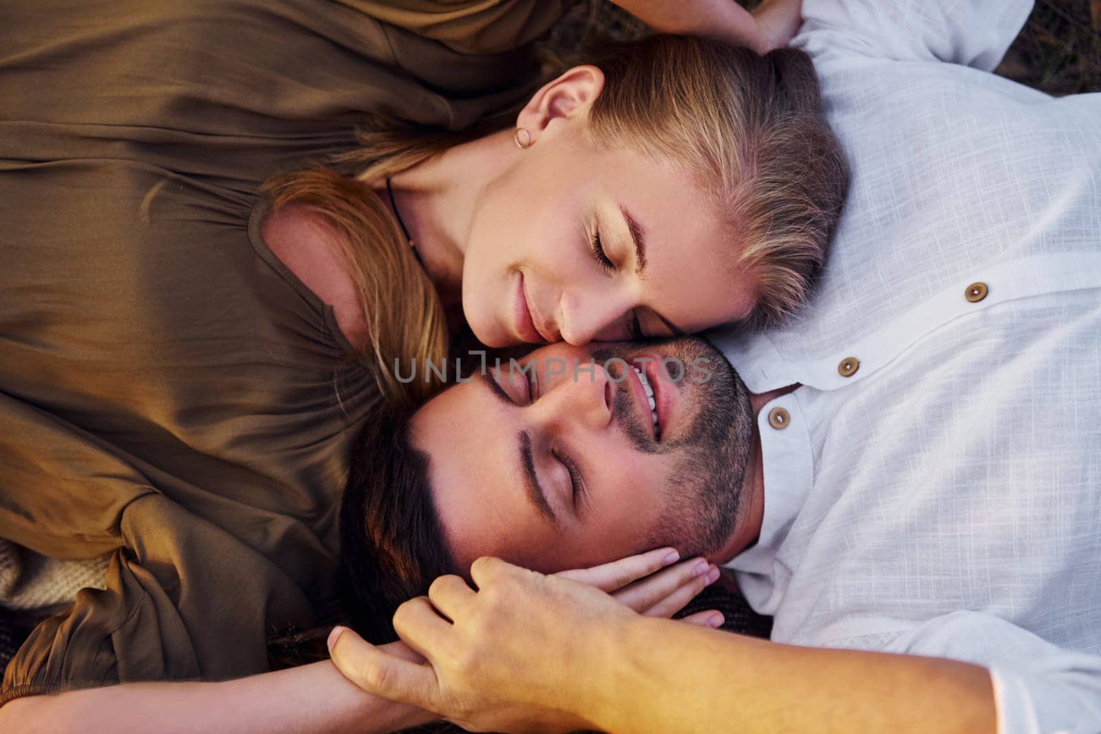 Happy couple is outdoors laying down on the ground.