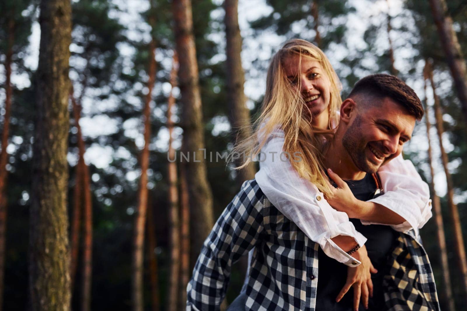 Happy couple is outdoors in the forest at daytime.