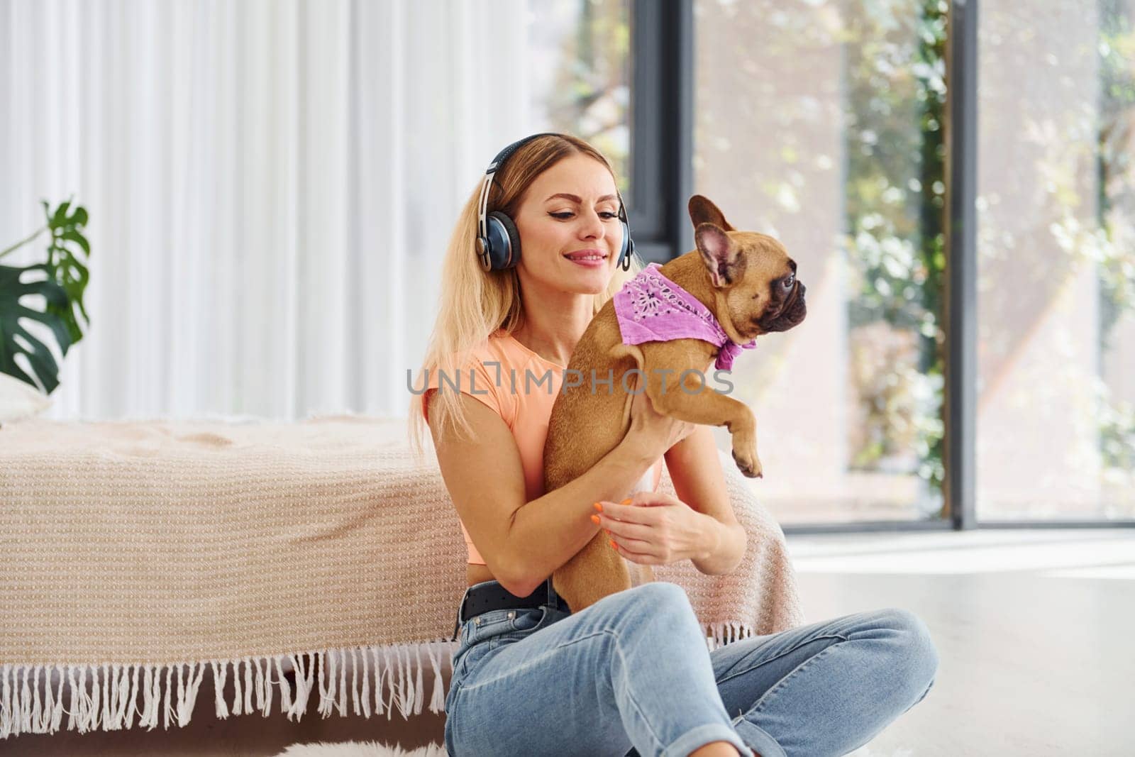 Sitting on the floor. Woman with pug dog is at home at daytime.