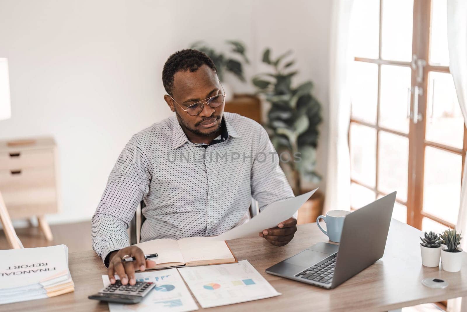 Portrait of handsome African black young business man working on laptop at office desk...