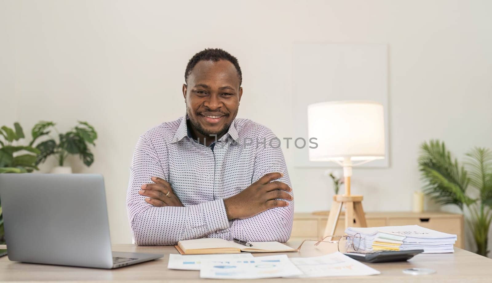 Portrait of handsome African black young business man working on laptop at office desk...