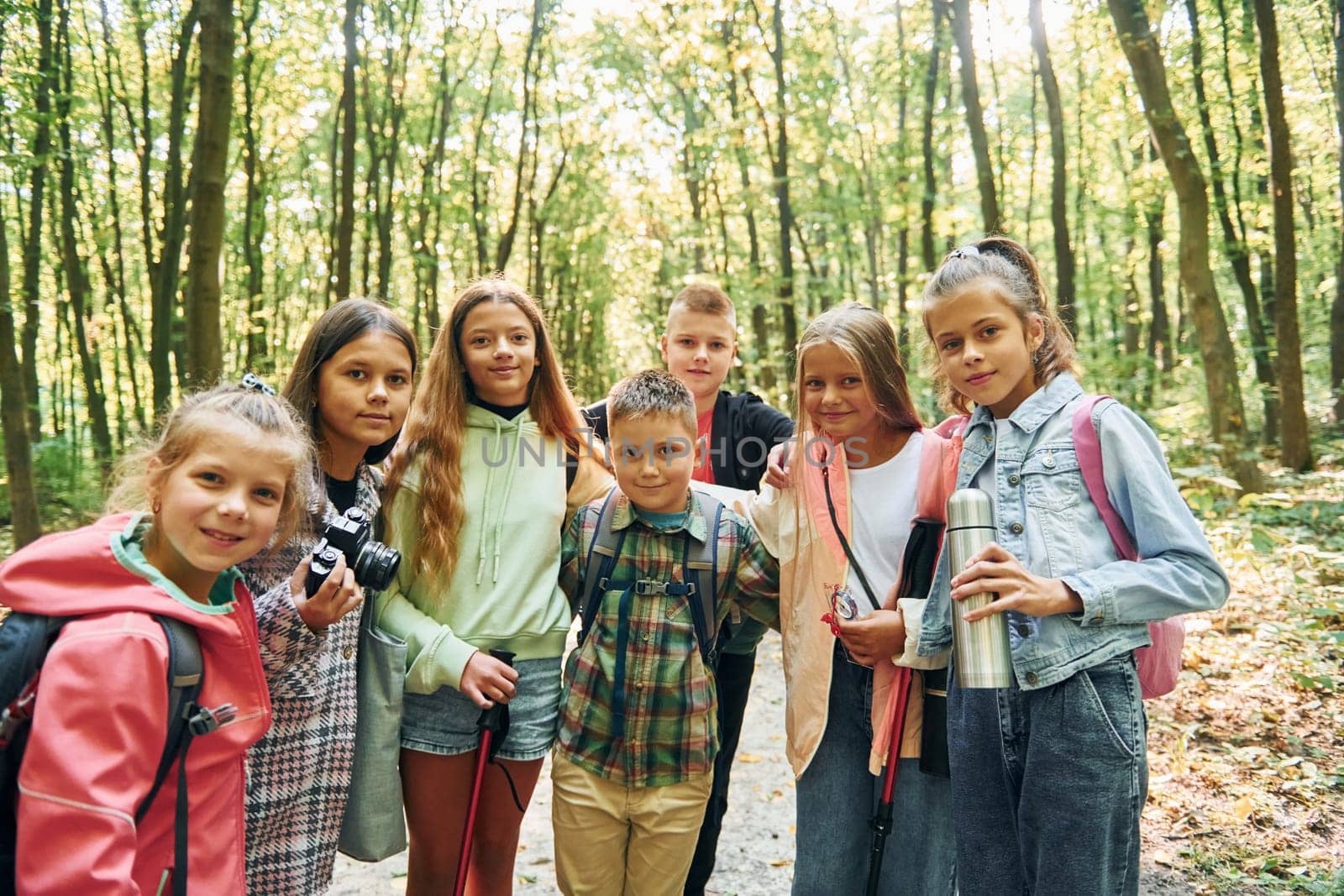 Standing together. Kids in green forest at summer daytime together.