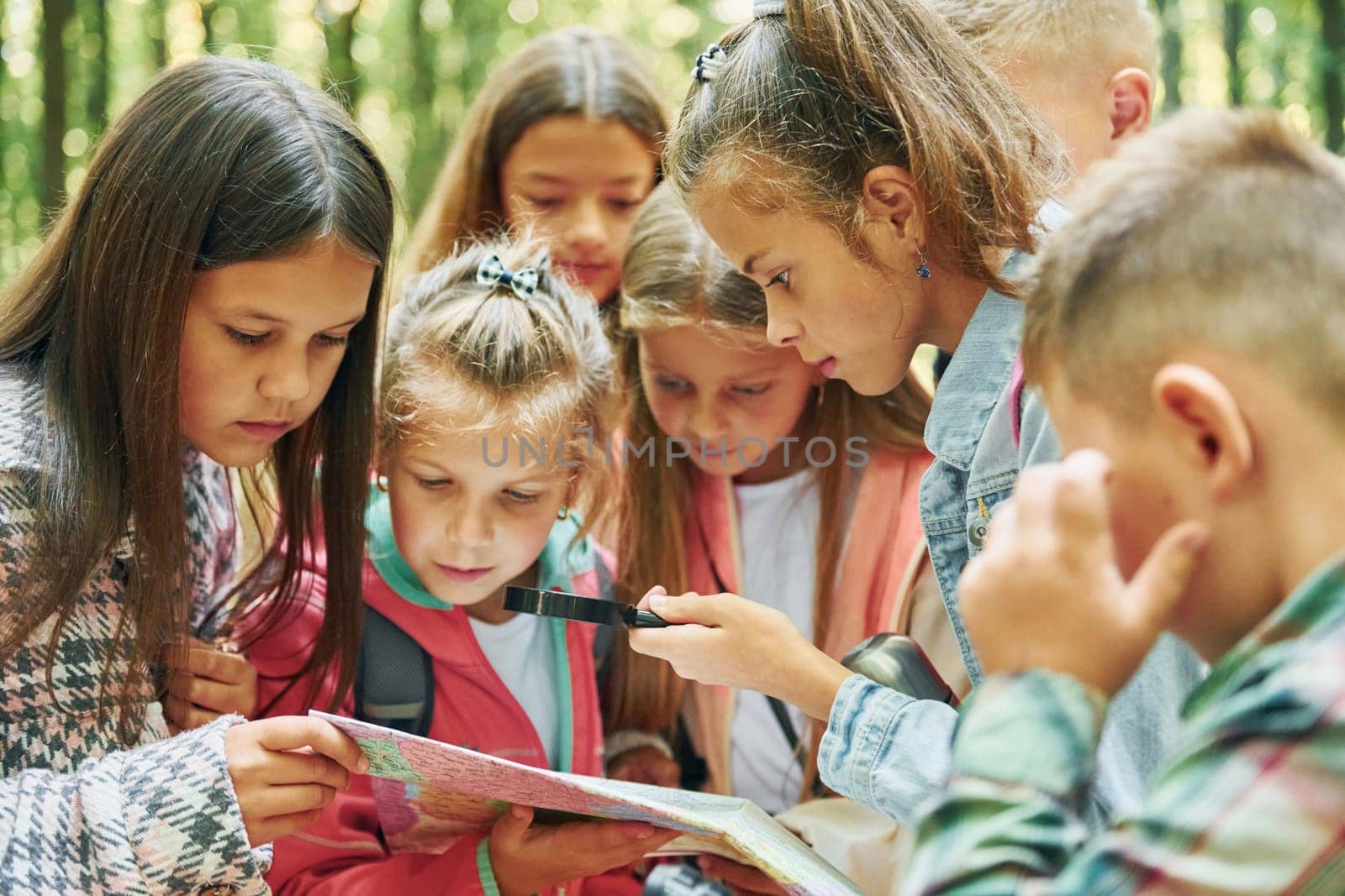 With map. Kids in green forest at summer daytime together.