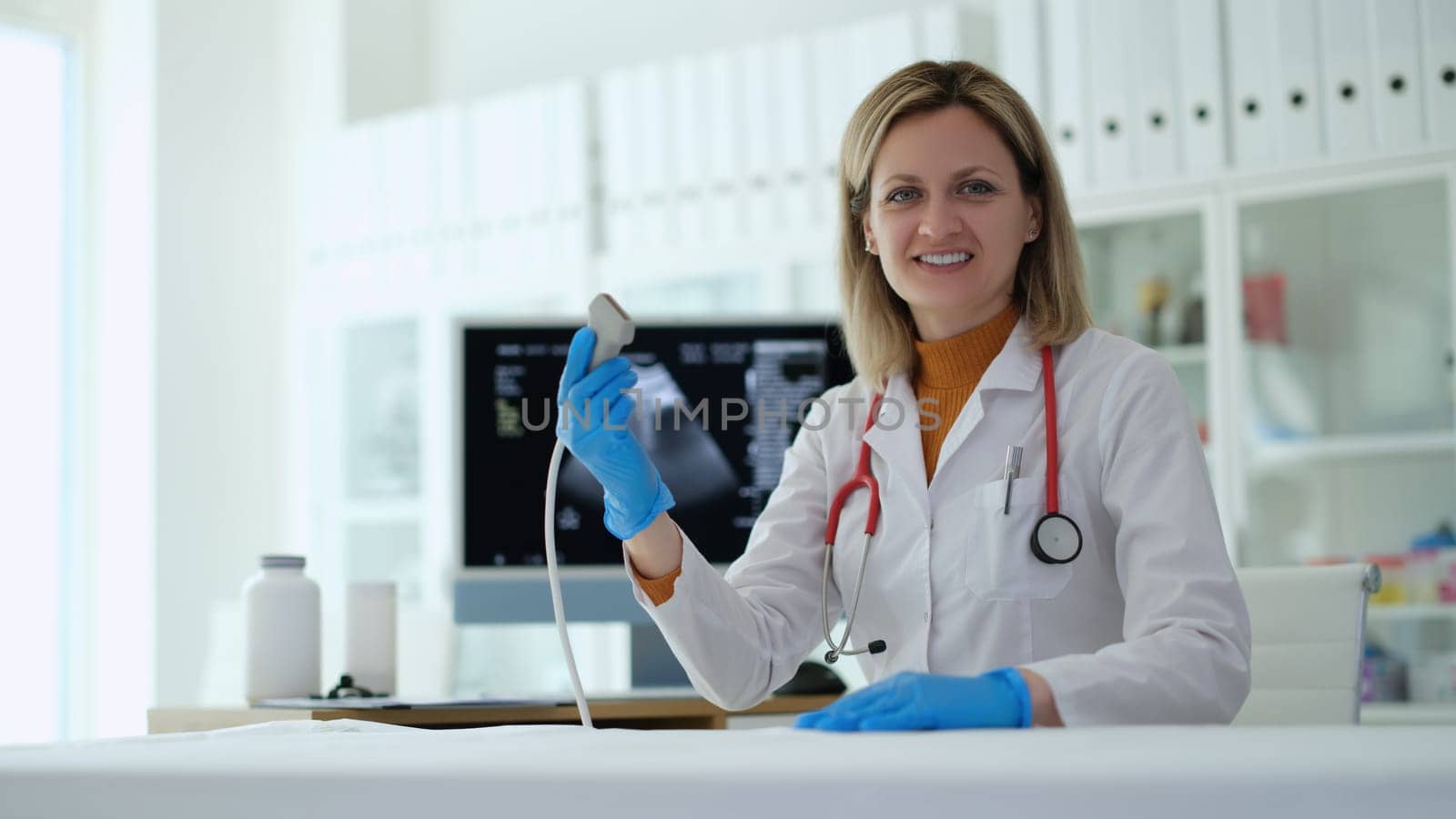 Woman doctor holding ultrasonic machine probe in clinic by kuprevich