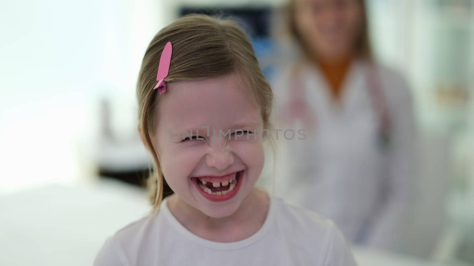 Little funny girl laughing at doctor appointment at clinic. High quality professional medical care for children pediatrics concept
