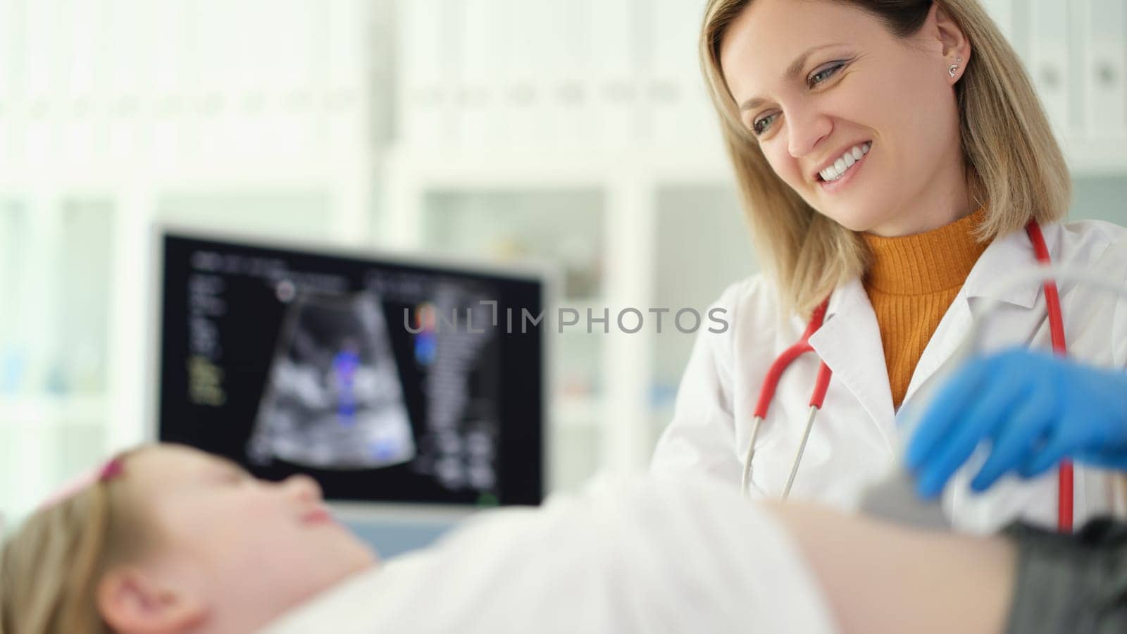 Doctor pediatrician conducting abdominal ultrasound examination of internal organs of child in clinic. Diagnosis of treatment of diseases of gastrointestinal tract in children concept