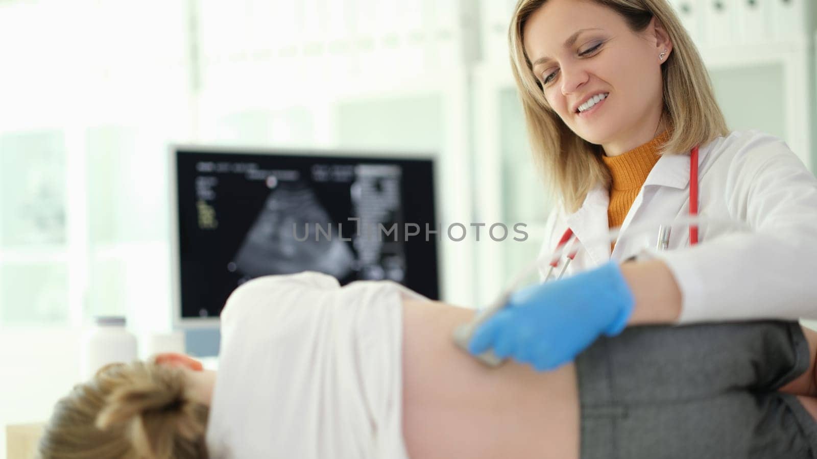 Doctor pediatrician conducting ultrasound examination of kidneys of child in clinic. Instrumental diagnosis of diseases and genitourinary system in children concept