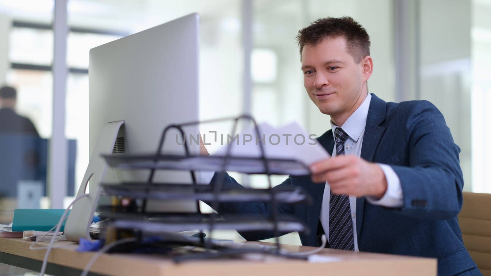 Smiling businessman taking documents to work in office. Paperwork concept