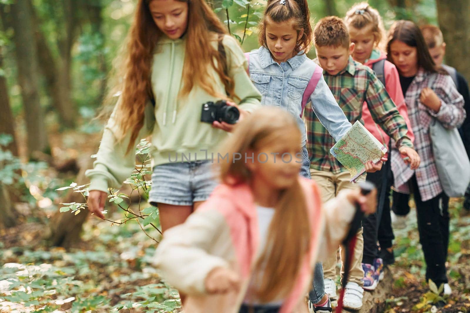 With touristic equipment. Kids in green forest at summer daytime together.