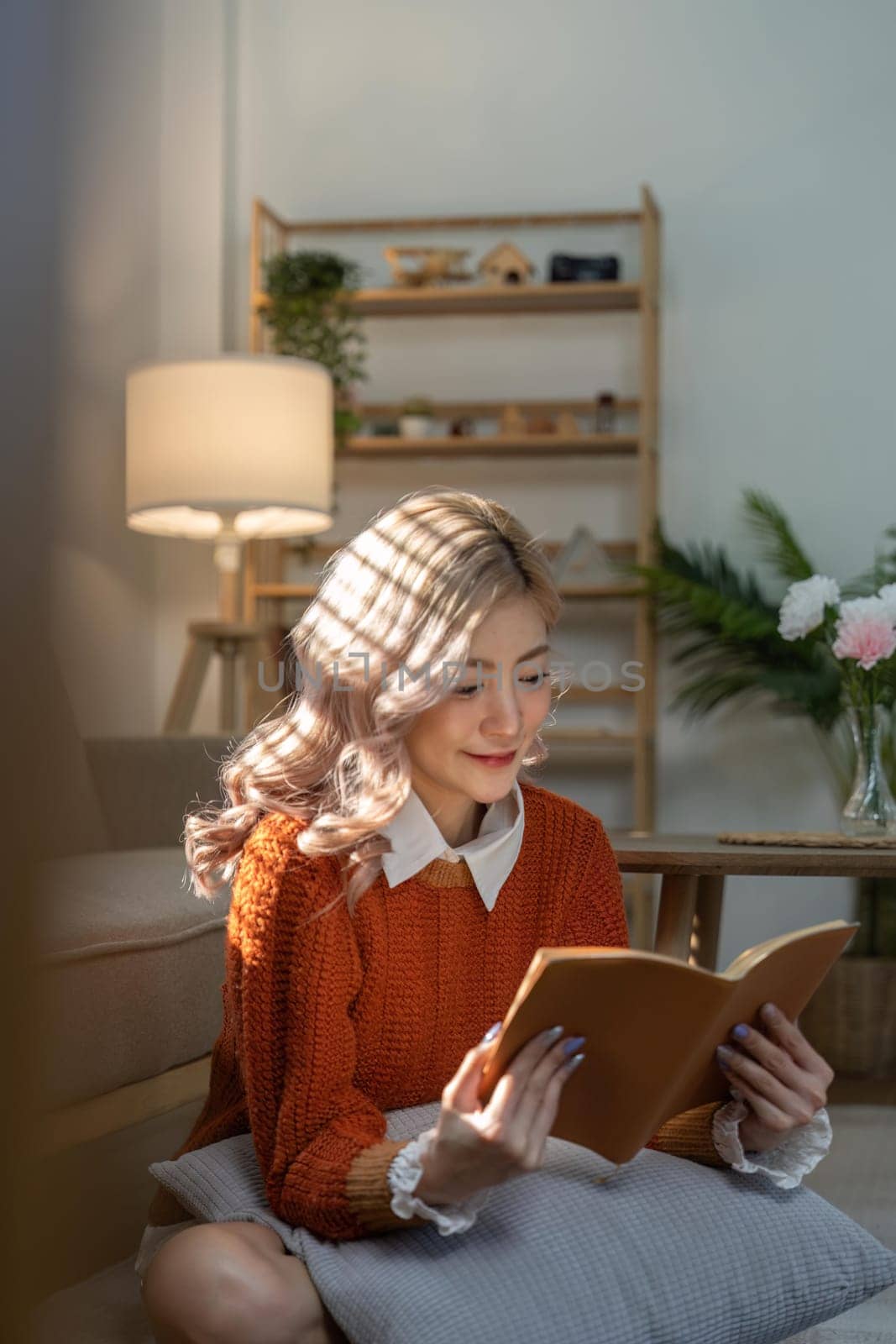 Young asian woman relax on couch at cozy home read interesting book. Happy female rest on sofa in living room enjoy novel or story on weekend.