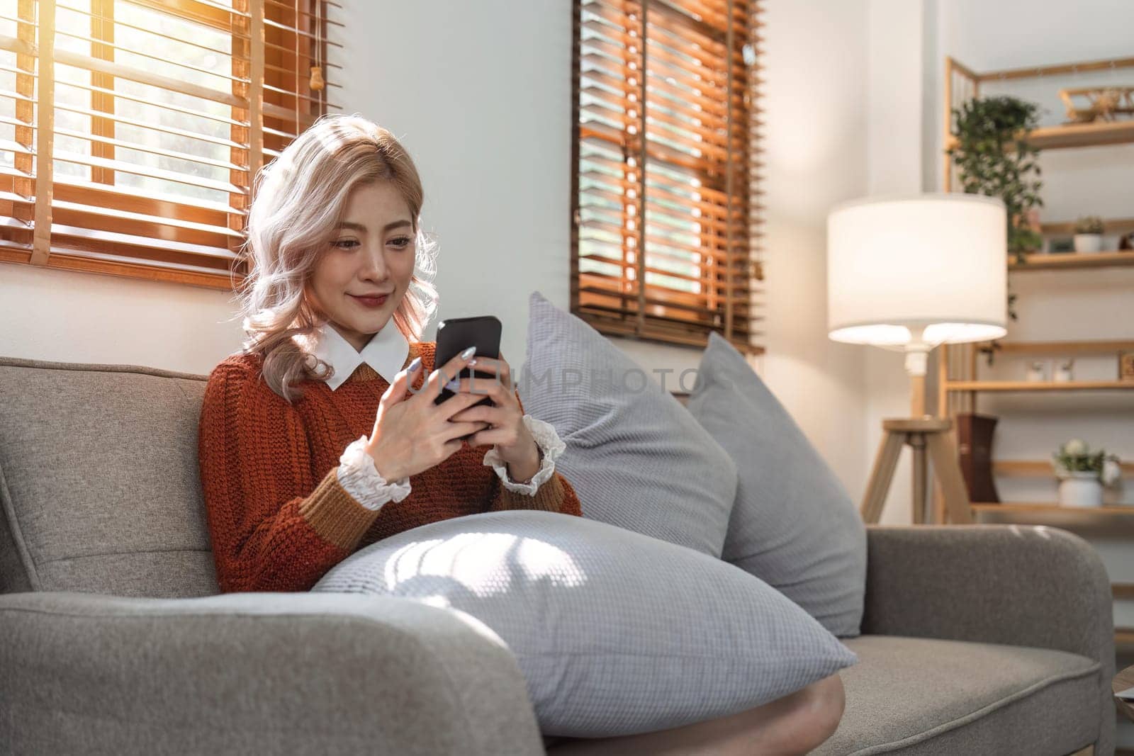 woman beautiful happy young woman resting on comfortable sofa, using cellphone application, web surfing useful information, playing games, shopping online.