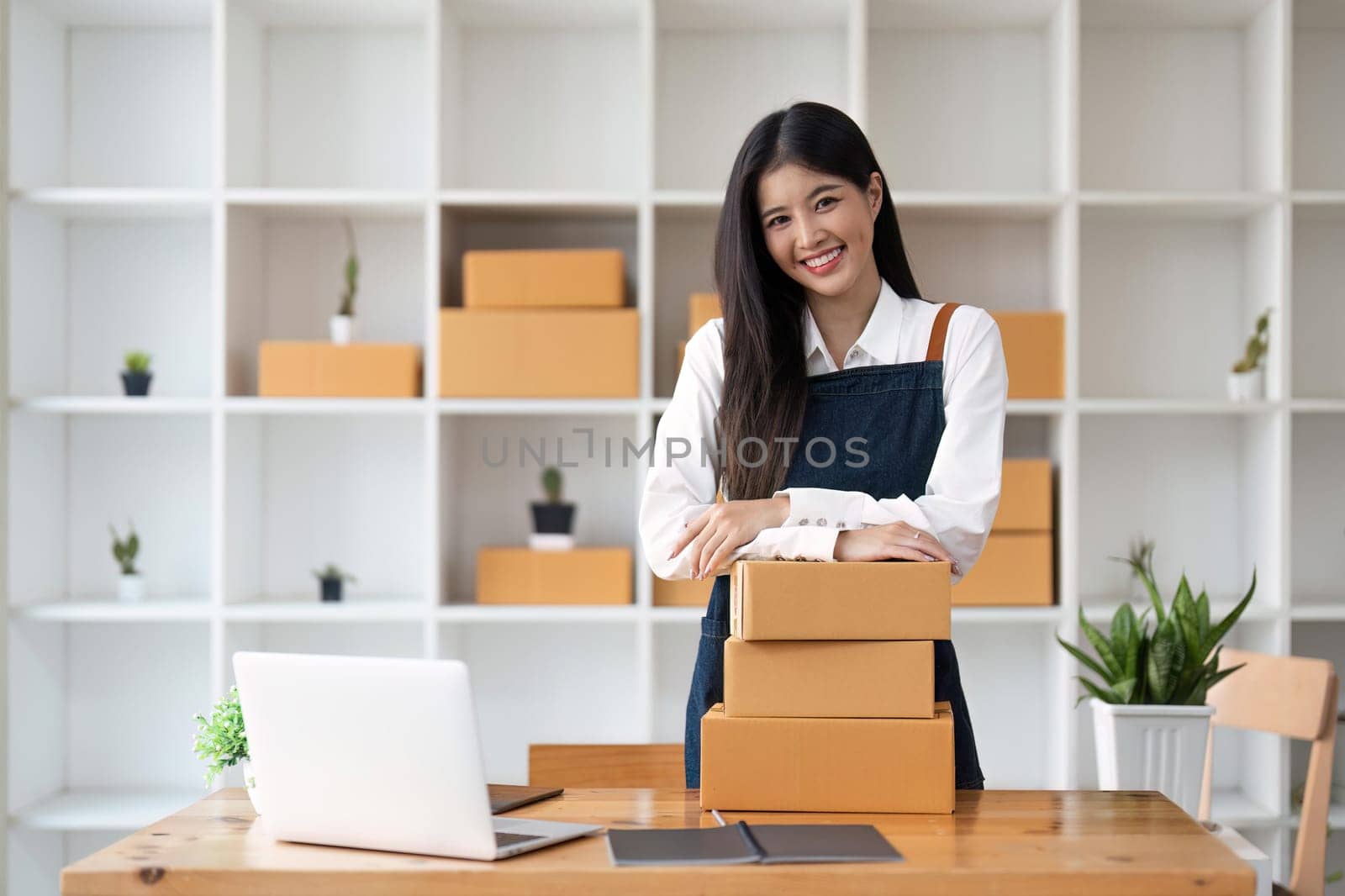 Young pretty asian start up business woman in apron working with online parcel box warehouse selling online product.