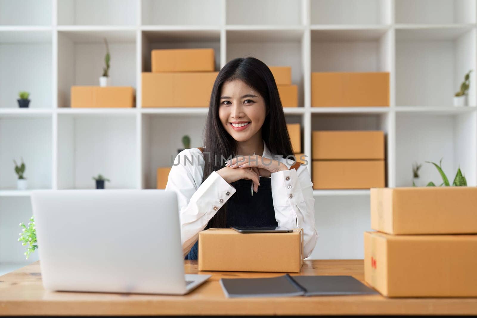 Young pretty asian start up business woman in apron working with online parcel box warehouse selling online product by nateemee