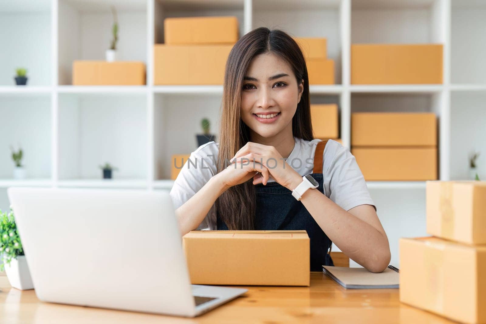 Young pretty asian start up business woman in apron working with online parcel box warehouse selling online product.