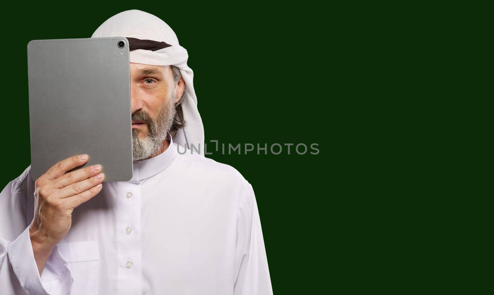 Islamic censorship online. Muslim Arab person holding tablet PC covering half of face symbolize concept of issues of privacy, security, and anonymity in digital world with modern and contemporary lifestyle perspective. by LipikStockMedia