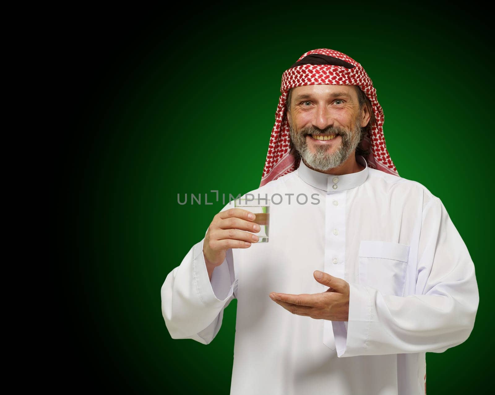 Arab man holding glass of water, conveying sense of healthy living and mindfulness. It emphasizes importance of hydration and wellness in Middle Eastern culture, making it ideal for use in health. High quality photo