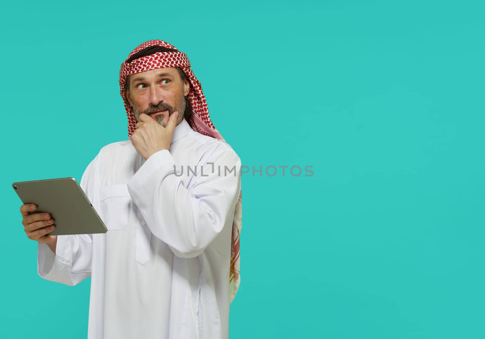Online shopping in Middle East. Arab man holds tablet and selects goods and services. High quality photo