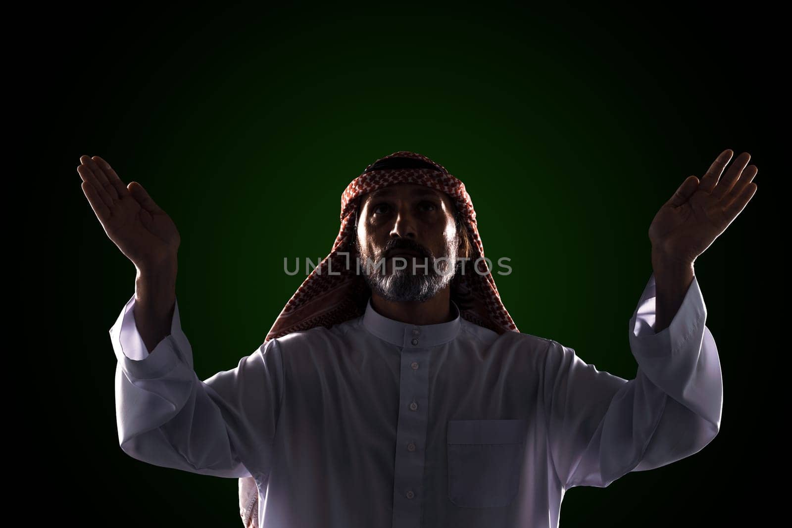 Muslim man raises his hands to sky in prayer and praise, expressing his devotion and faith in One God of Allah. Spirituality and traditional practices of Islamic culture and religion.