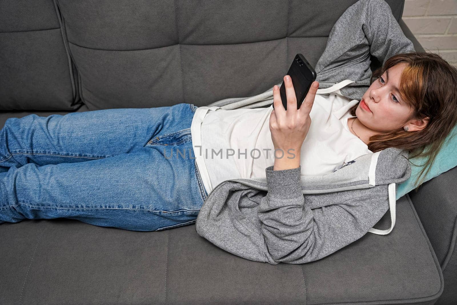 girl is lying on the couch and holding a smartphone in her hands by audiznam2609
