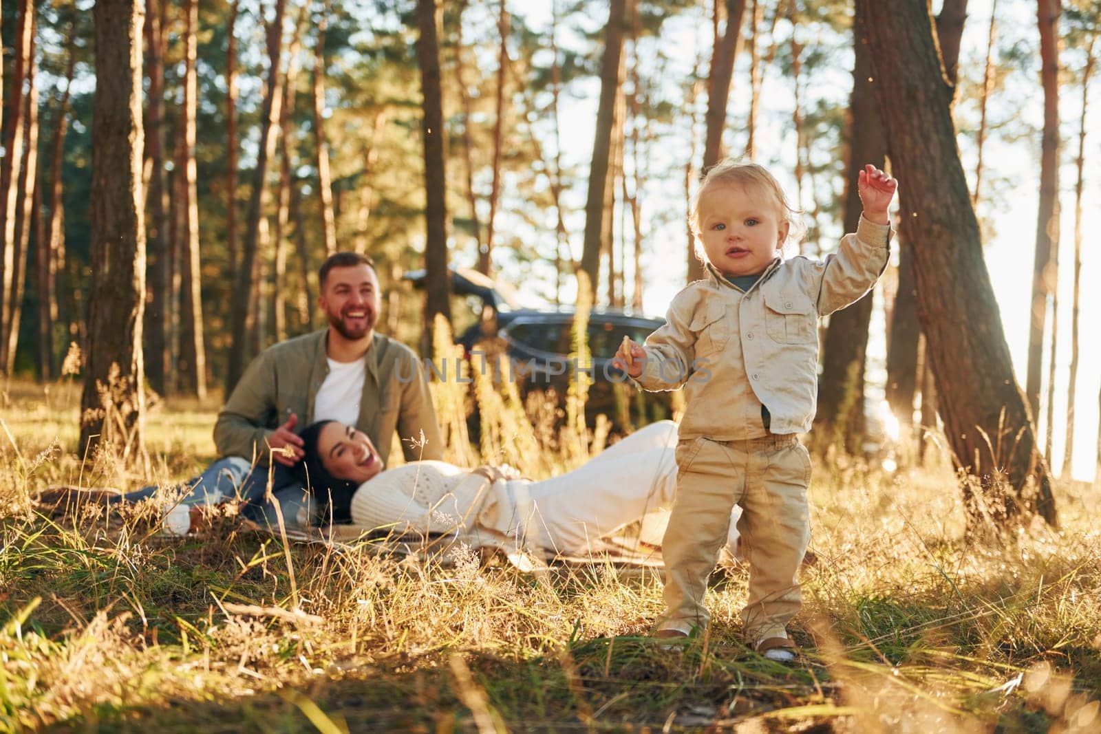 Girl is having a walk. Happy family of father, mother and little daughter is in the forest.