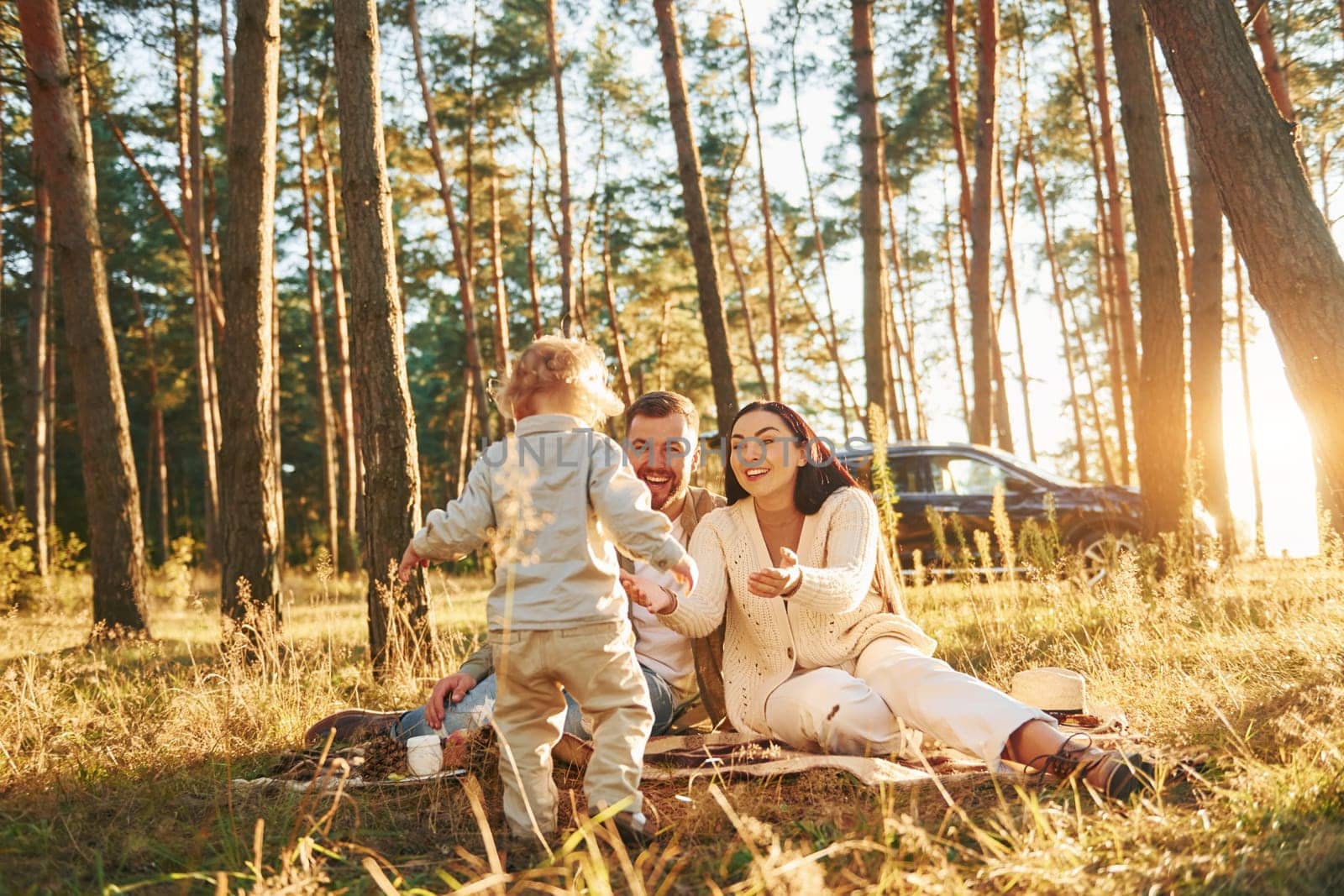 Positive emotions. Happy family of father, mother and little daughter is in the forest by Standret