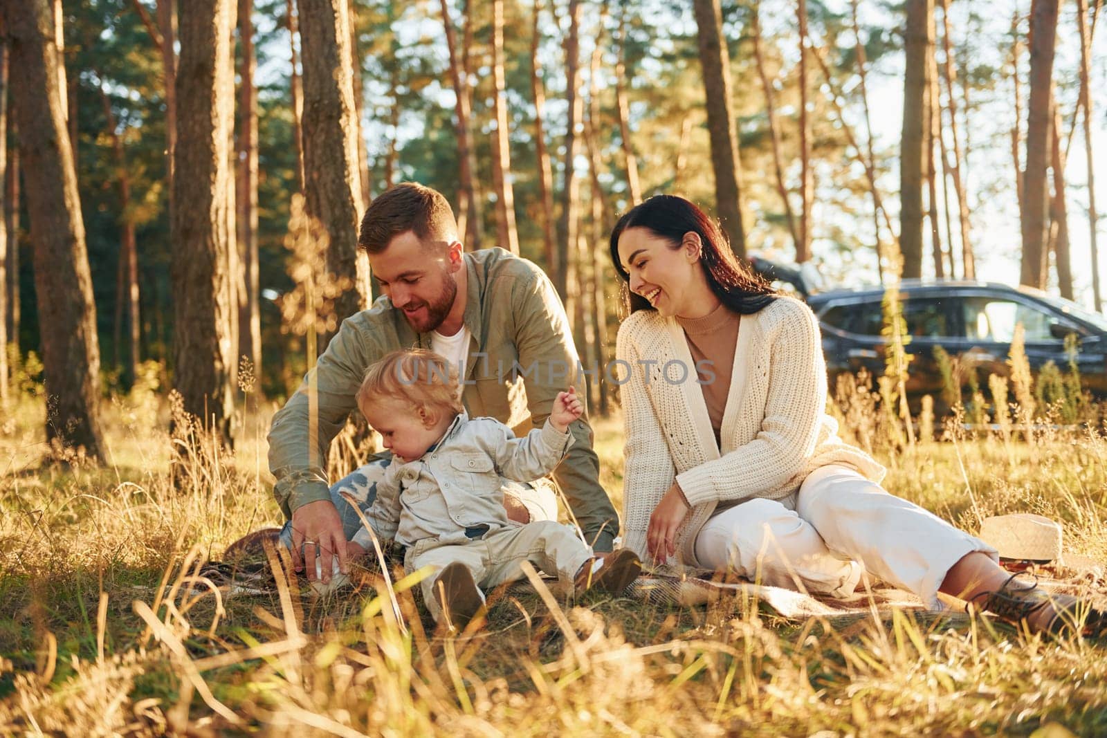 Positive emotions. Happy family of father, mother and little daughter is in the forest by Standret