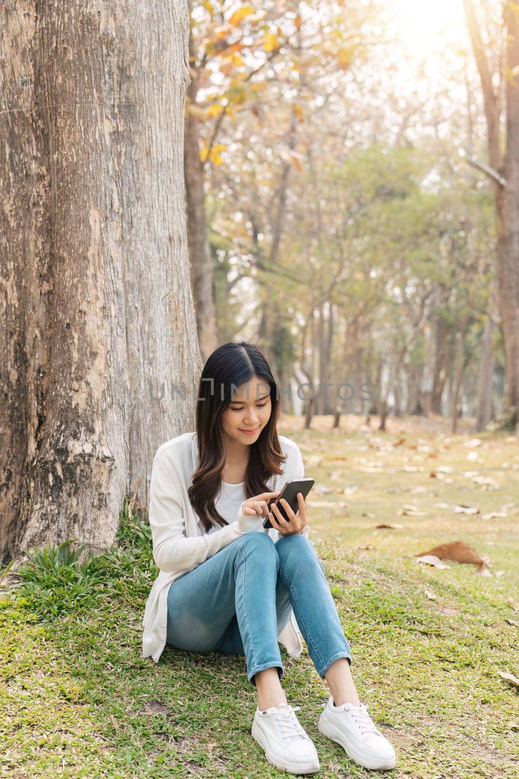 young smiling woman in on in park outdoors rest use mobile cell phone see news online. People urban lifestyle concept.